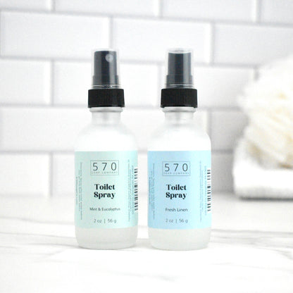 Two bottles of 570 Toilet Spray on a white surface with a blurred background