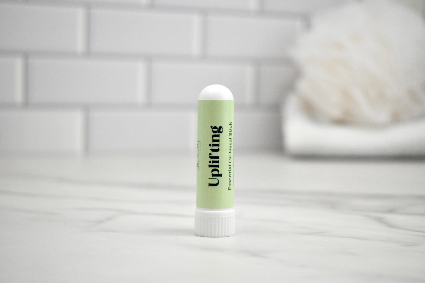 Nasal stick labeled 'Uplifting' on a white surface with a light gray tiled wall background