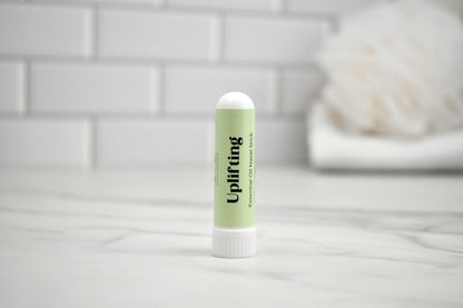 Nasal stick labeled 'Uplifting' on a white surface with a light gray tiled wall background