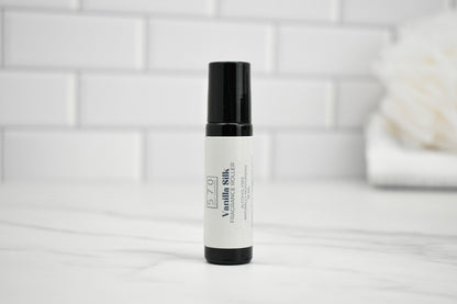 White rollerball bottle with black cap on a white surface with a light gray tiled wall background