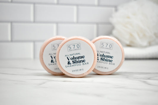 Three shampoo bars labeled '570 Volume & Shine' on a white surface with a tiled wall background.