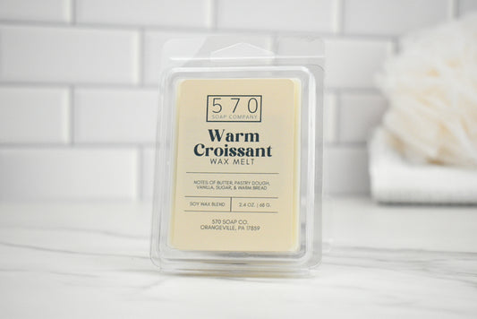 Wax melt packaging labeled '570 Warm Croissant' on a white surface with a blurred background.