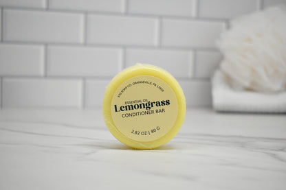 Yellow lemongrass conditioner bar on a white surface with a tiled wall background